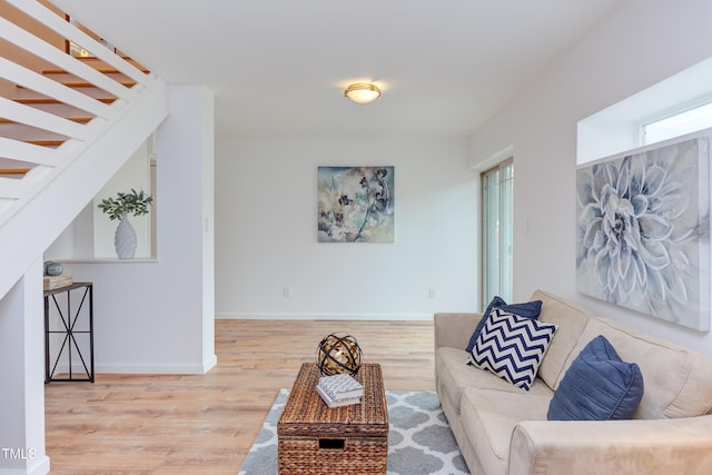 living area featuring stairs, baseboards, and wood finished floors