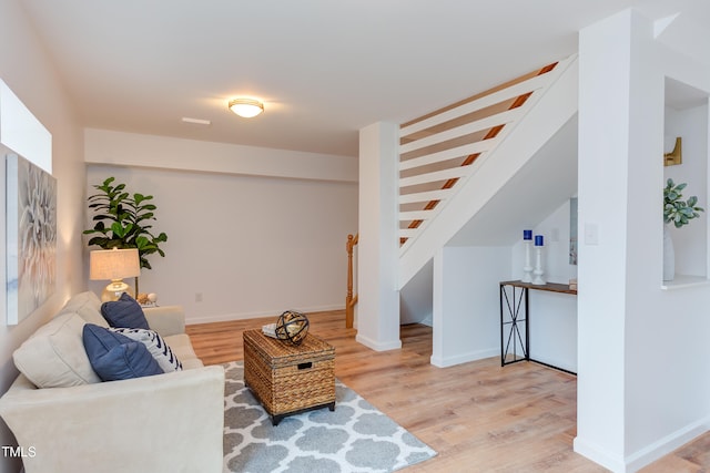 living area with stairway, wood finished floors, and baseboards