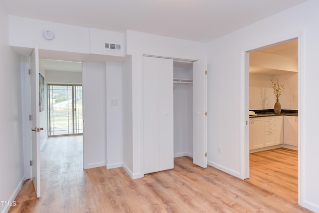 unfurnished bedroom featuring baseboards, visible vents, and light wood finished floors