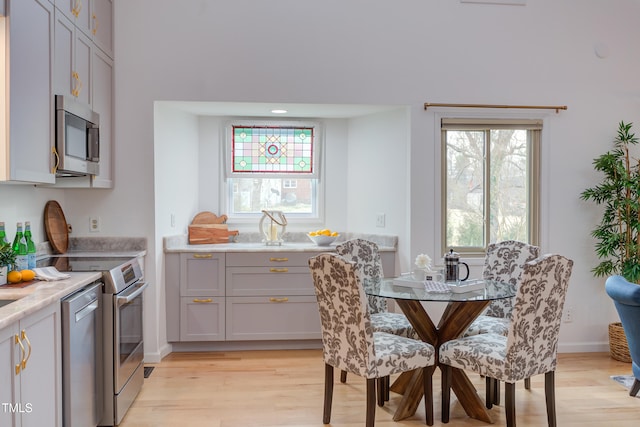 kitchen featuring stainless steel appliances, light wood-type flooring, gray cabinets, and baseboards