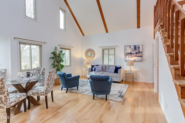 living area featuring light wood finished floors, baseboards, high vaulted ceiling, and beam ceiling