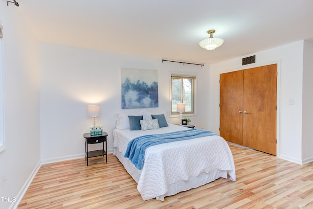 bedroom featuring a closet, visible vents, light wood-style flooring, and baseboards