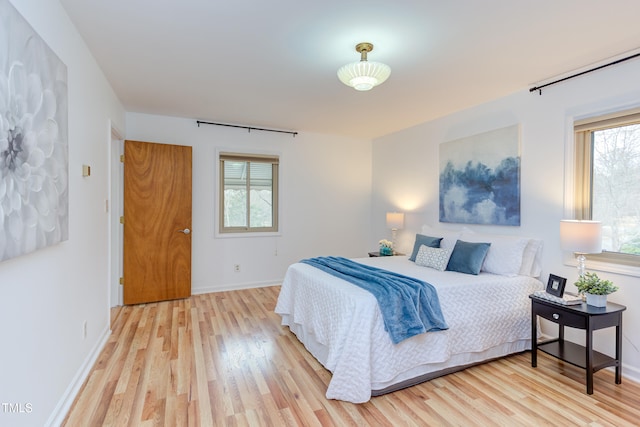 bedroom featuring light wood-style flooring, multiple windows, and baseboards