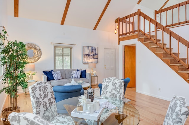 living area featuring baseboards, wood finished floors, beamed ceiling, stairs, and high vaulted ceiling