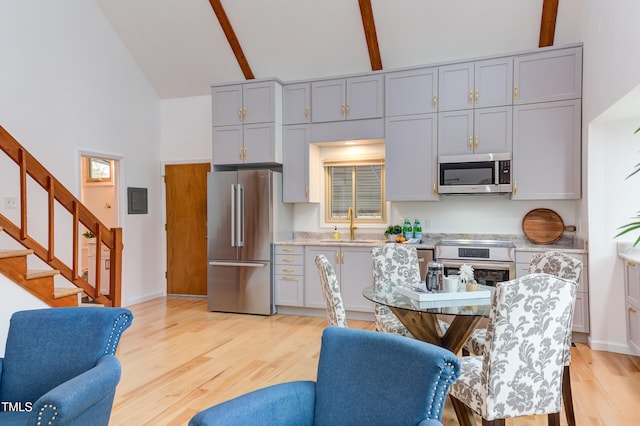 kitchen featuring appliances with stainless steel finishes, open floor plan, light countertops, and beamed ceiling