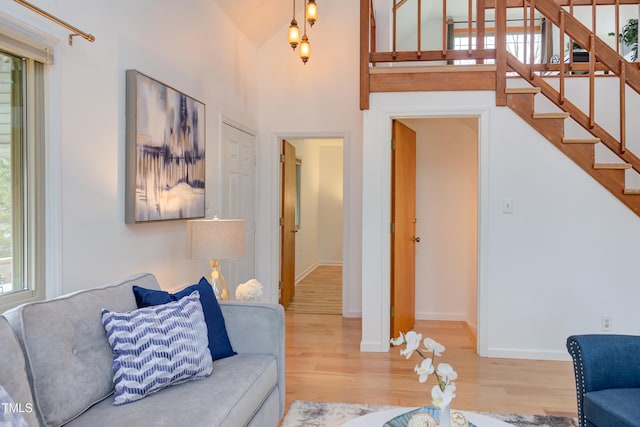 living room featuring stairs, wood finished floors, a towering ceiling, and baseboards