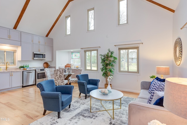 living area with light wood-type flooring, baseboards, high vaulted ceiling, and beam ceiling