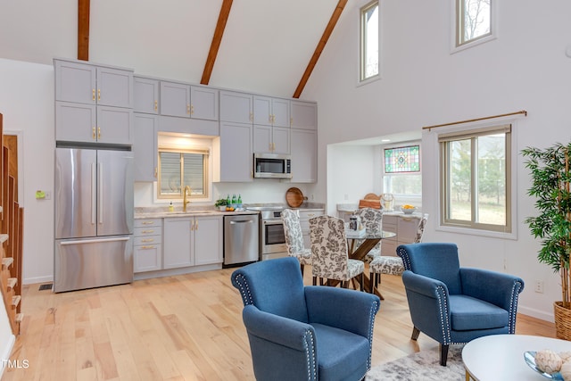 kitchen featuring appliances with stainless steel finishes, open floor plan, light countertops, and a sink