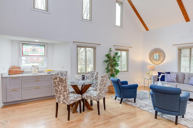 dining space with high vaulted ceiling, light wood-type flooring, and a healthy amount of sunlight