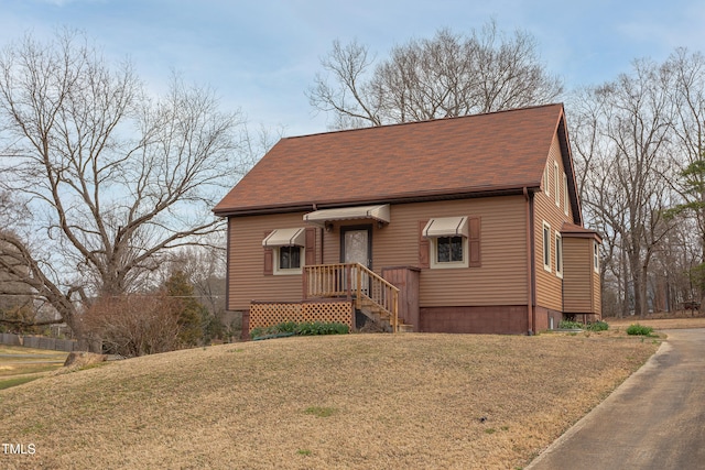 view of front facade featuring a shingled roof and a front lawn