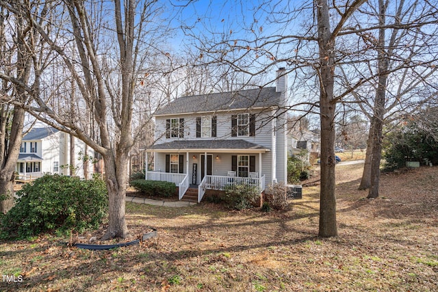 view of front of home featuring roof with shingles, a porch, and a chimney