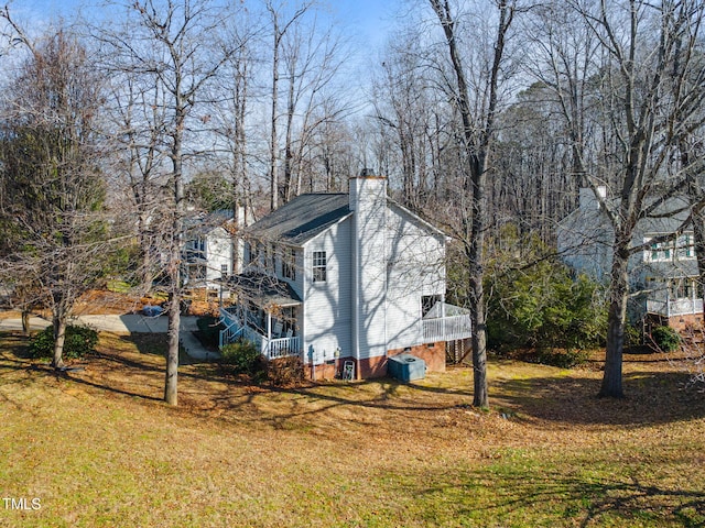 view of property exterior with a chimney, cooling unit, and a lawn