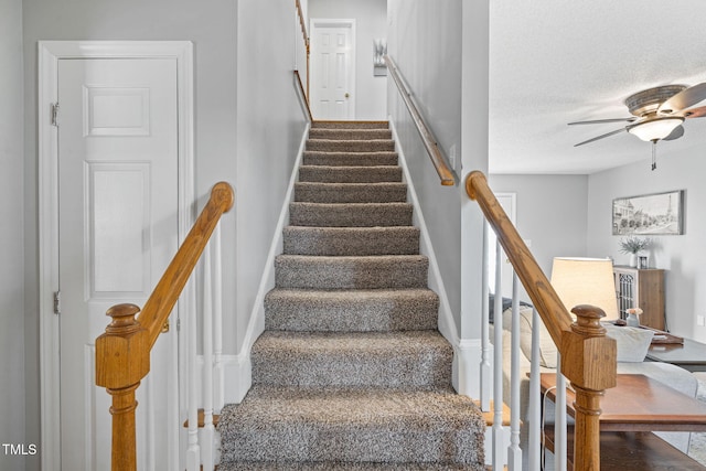 stairs with baseboards, a ceiling fan, and a textured ceiling