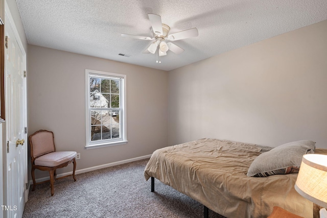 carpeted bedroom featuring a ceiling fan, baseboards, visible vents, and a textured ceiling