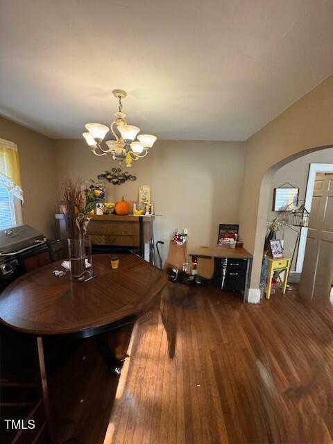 dining room with arched walkways, wood finished floors, and a chandelier