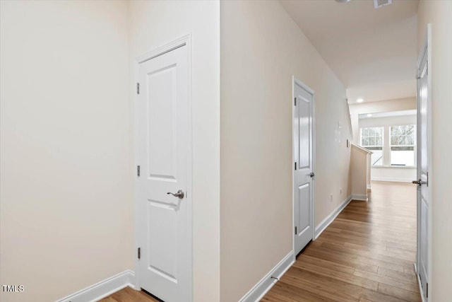 corridor featuring baseboards and wood finished floors