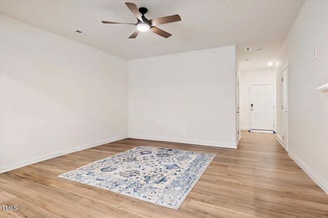 spare room with baseboards, ceiling fan, visible vents, and light wood-style floors