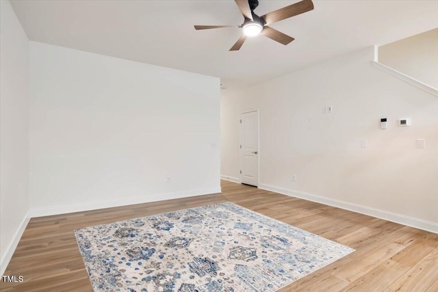 empty room featuring light wood-style floors, baseboards, and a ceiling fan