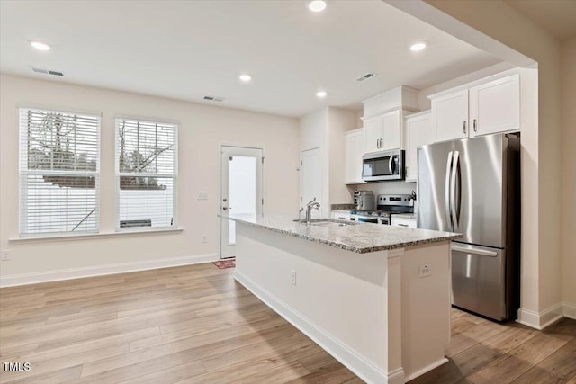 kitchen with appliances with stainless steel finishes, light wood-style flooring, a sink, and white cabinetry