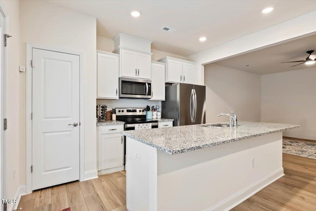 kitchen featuring stainless steel appliances, visible vents, a sink, and light wood finished floors