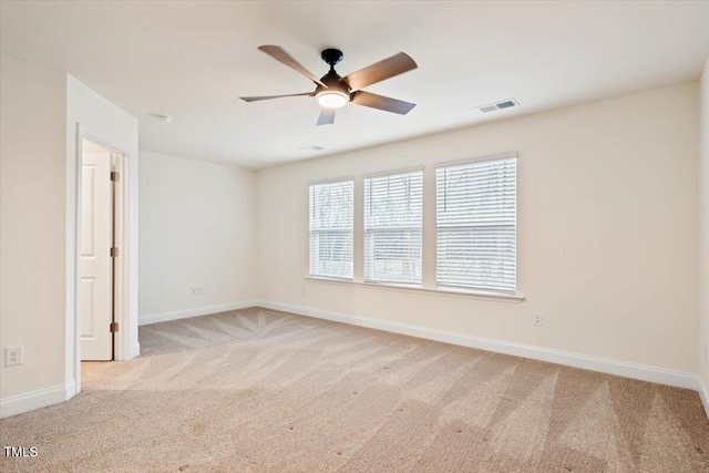 empty room with light carpet, a ceiling fan, visible vents, and baseboards