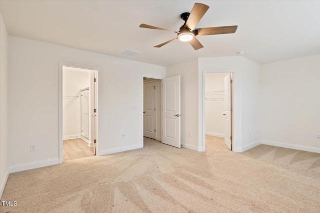 unfurnished bedroom with baseboards, carpet flooring, visible vents, and a walk in closet