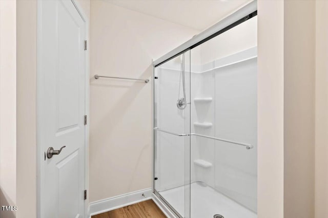 full bathroom with a shower stall, baseboards, and wood finished floors