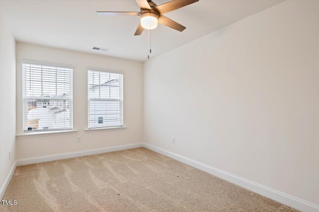 empty room with carpet flooring, ceiling fan, visible vents, and baseboards