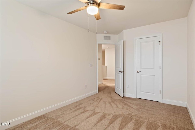 unfurnished bedroom with light colored carpet, ceiling fan, visible vents, and baseboards