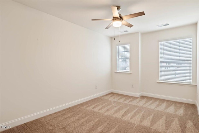 unfurnished room featuring baseboards, visible vents, ceiling fan, and light colored carpet