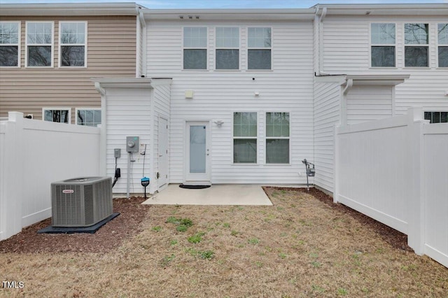 rear view of house with cooling unit, a patio area, fence, and a lawn