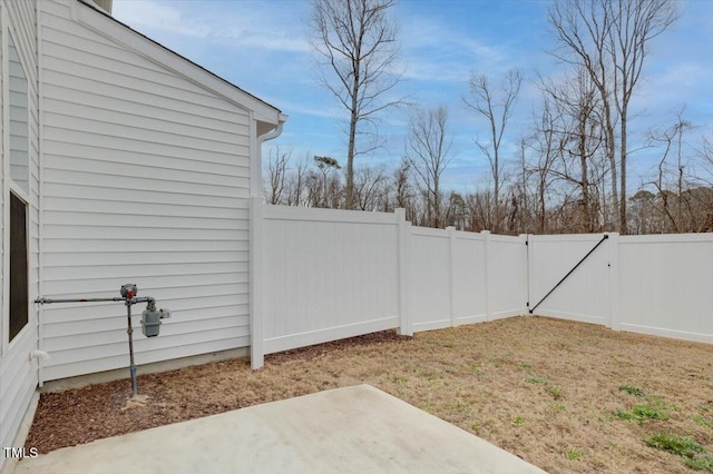 view of yard featuring a patio area, a fenced backyard, and a gate