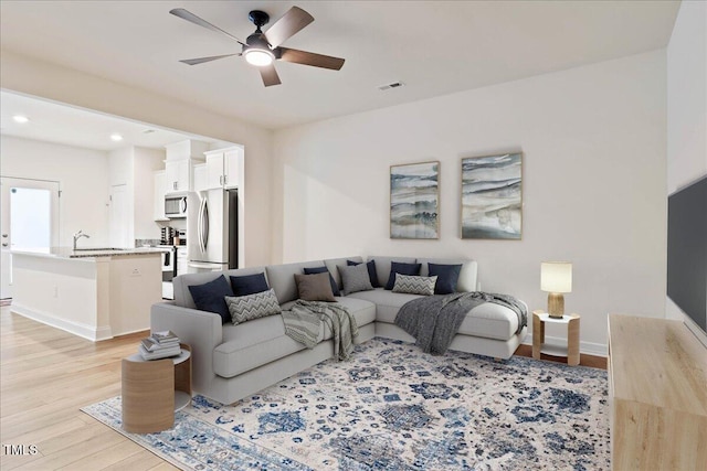 living area featuring light wood-style flooring, baseboards, a ceiling fan, and recessed lighting