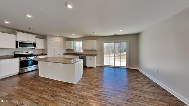 kitchen with white cabinetry, appliances with stainless steel finishes, dark stone counters, and a center island