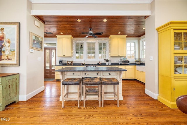 kitchen with a breakfast bar, dark countertops, glass insert cabinets, and a center island