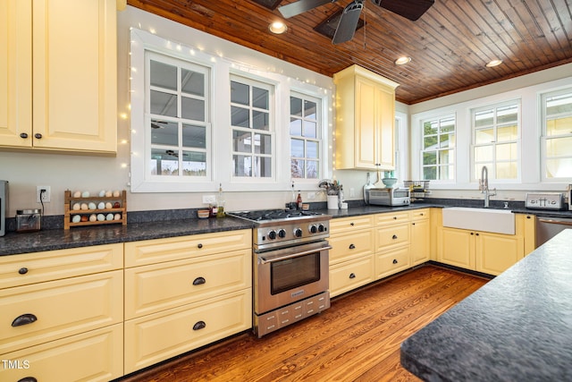 kitchen with a sink, wood ceiling, appliances with stainless steel finishes, dark countertops, and dark wood finished floors