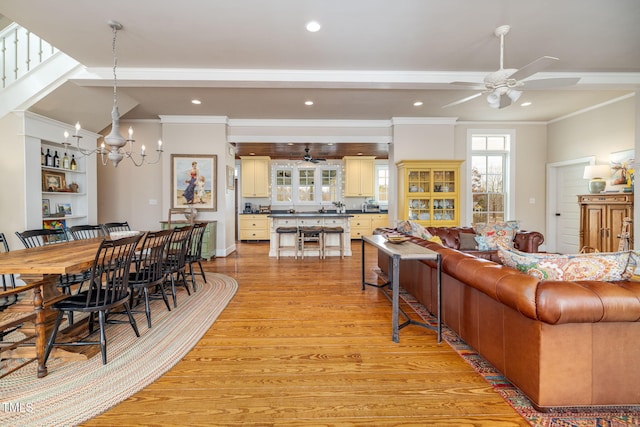 living area featuring ceiling fan with notable chandelier, recessed lighting, light wood-style flooring, and crown molding