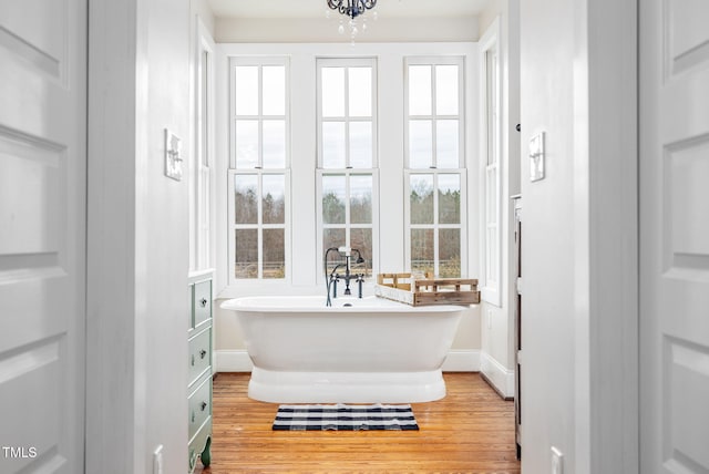 full bath featuring wood finished floors, a freestanding tub, and baseboards