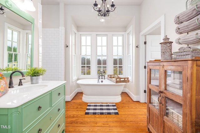 bathroom with vanity, baseboards, a freestanding bath, and wood finished floors