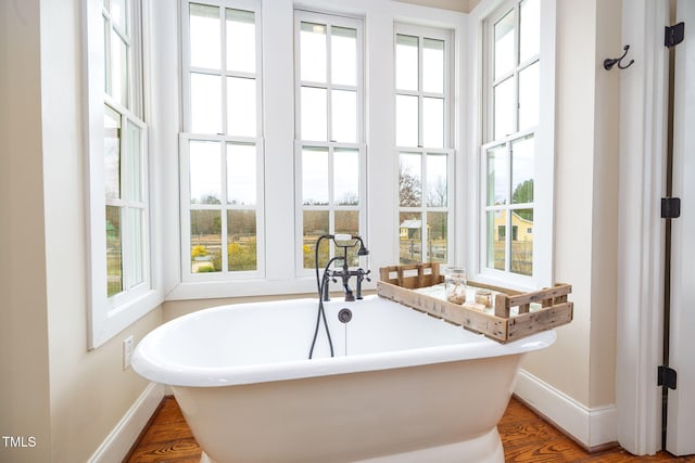 bathroom featuring a freestanding bath, wood finished floors, and baseboards