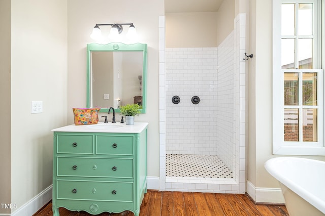 full bathroom with a stall shower, baseboards, wood finished floors, a freestanding bath, and vanity