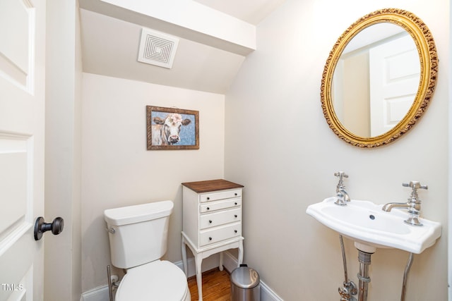 half bathroom with baseboards, visible vents, toilet, and wood finished floors