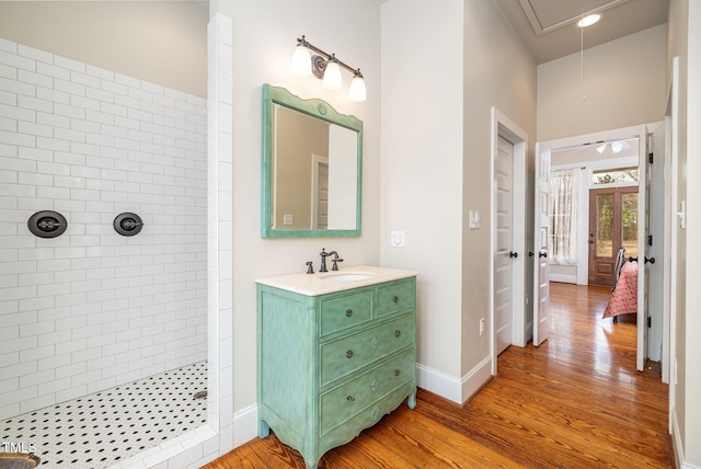 bathroom with baseboards, tiled shower, wood finished floors, and vanity