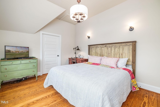 bedroom with lofted ceiling, a notable chandelier, light wood-style flooring, and baseboards