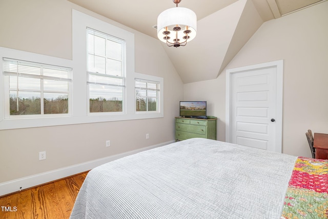 bedroom featuring lofted ceiling, an inviting chandelier, baseboards, and wood finished floors