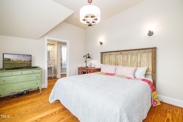 bedroom featuring baseboards, lofted ceiling, connected bathroom, and light wood-style floors