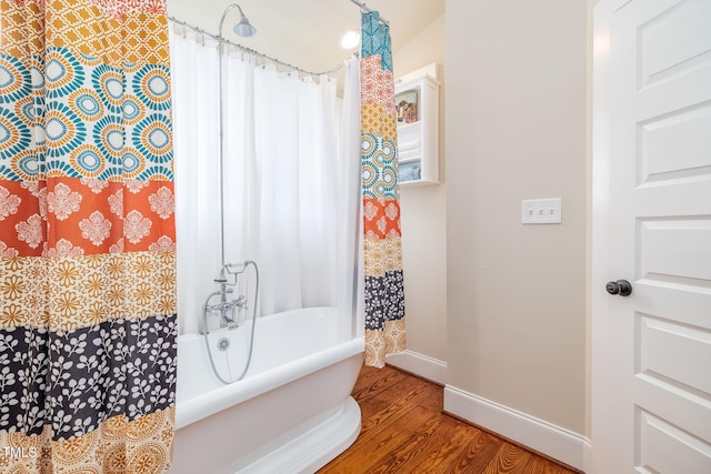 bathroom with shower / bathtub combination with curtain, baseboards, and wood finished floors