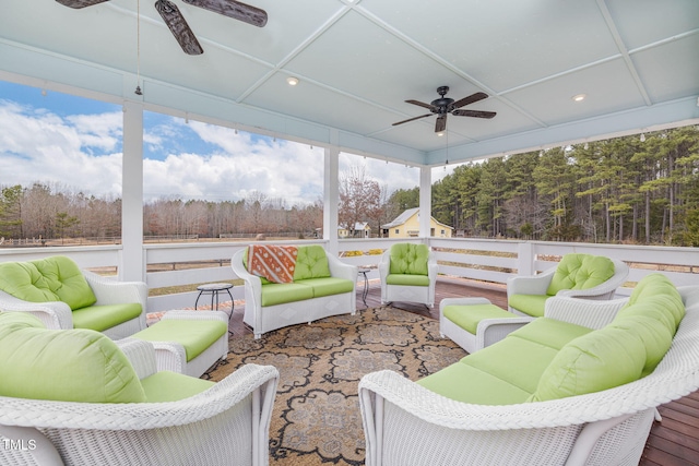 sunroom / solarium with a forest view, coffered ceiling, and a ceiling fan