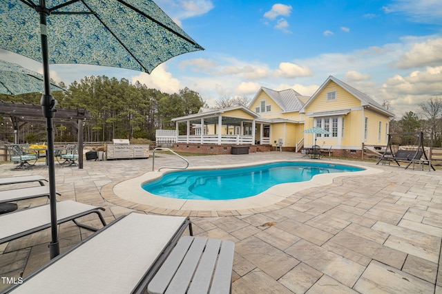 outdoor pool featuring a patio area, exterior kitchen, fence, and a pergola