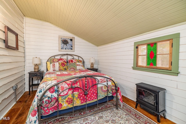 bedroom featuring dark wood-style floors, lofted ceiling, a wood stove, and wooden walls